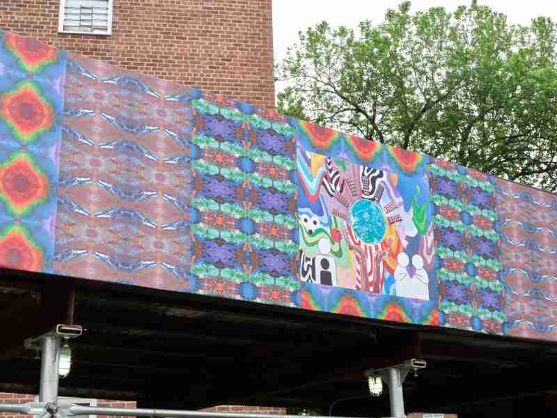 On July 8, a new art exhibition, “Present Power / Future Hopes,” brought outdoor art indoors to showcase the work of 59 New York-based artists who created 25,000 square feet of art to help beautify and bring public art to 17 NYCHA developments across the city. The exhibition is produced by ArtBridge as a culmination of its Bridging the Divide program, a fellowship in which local artists design temporary public artworks that reflect the lives, histories, and aspirations of NYCHA residents. The artists created over 50 new, site-specific artwork that was affixed to construction fencing and sidewalk sheds at each location, as made possible through the NYC Department of Cultural Affairs’ City Canvas pilot initiative. As part of the fellowship, the artists held hundreds of art workshops and community events with NYCHA residents. (See past NYCHA Journal stories on Bridging the Divide here.)