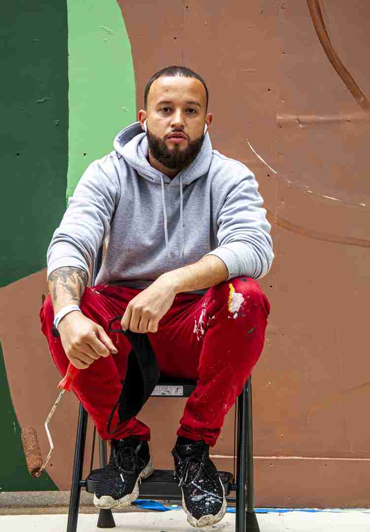 Alexandre Keto sitting in front of his mural on 6th avenue and 43rd street in Manhattan. Photo by Pascal DuBois
