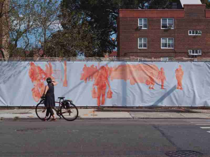 A woman holding her bicycle photographing art